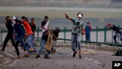 Warga Muslim Kashmir melemparkan batu-batu ke arah pasukan keamanan di Srinagar, Kashmir-India, Selasa (12/7). 