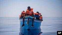 Kundi la wahamiaji wanaoaminika kuwa wahamiaji kutoka Tunisia wakiwa kwenye boti ya mbao wakisubiri kusaidiwa na timu ya shirika la hisani la Uispania, karibu na kisiwa cha Italy cha Lampedusa, Julai 29, 2021. Picha ya AP