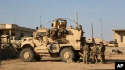 U.S. Army soldiers stand outside their armored vehicle on a joint base with Iraqi army south of Mosul, Iraq, Feb. 23, 2017. The new defense spending bill includes money for training to fight ISIS.