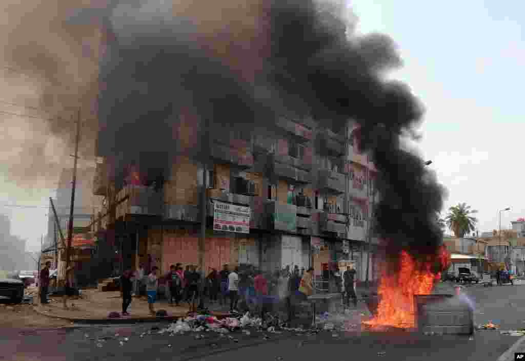 Anti-government protesters set a fire and block roads in Baghdad, Iraq.