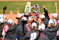 FILE - Oklahoma players celebrate with the trophy after defeating Florida State in the final game of the NCAA Women's College World Series softball championship in Oklahoma City, June 10, 2021.