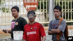 People wade through their flooded village of Wat Sukran Tharam in Ayutthaya as aid is delivered to a collective shelter October 13, 2011. Workers and soldiers raced to finish defensive walls around inner Bangkok on Thursday as floodwater that has covered 