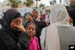 Para perempuan Palestina berduka di dekat jenazah kerabatnya yang tewas dalam serangan udara Israel, di luar kamar mayat Rumah Sakit Martir Al-Aqsa di Deir al Balah, Jalur Gaza, Senin, 10 Juni 2024. (Foto: AP)