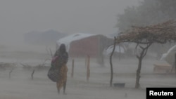 FILE A Sudanese woman who fled the conflict in Sudan's Darfur region, walks during a rainstorm at a refugee camp in Ourang on the outskirts of Adre, Chad July 30, 2023. 