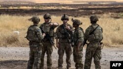 FILE - U.S. soldiers stand at an oil field in the countryside of al-Qahtaniyah town in Syria's northeastern Hasakeh province near the Turkish border, Aug. 4, 2020.