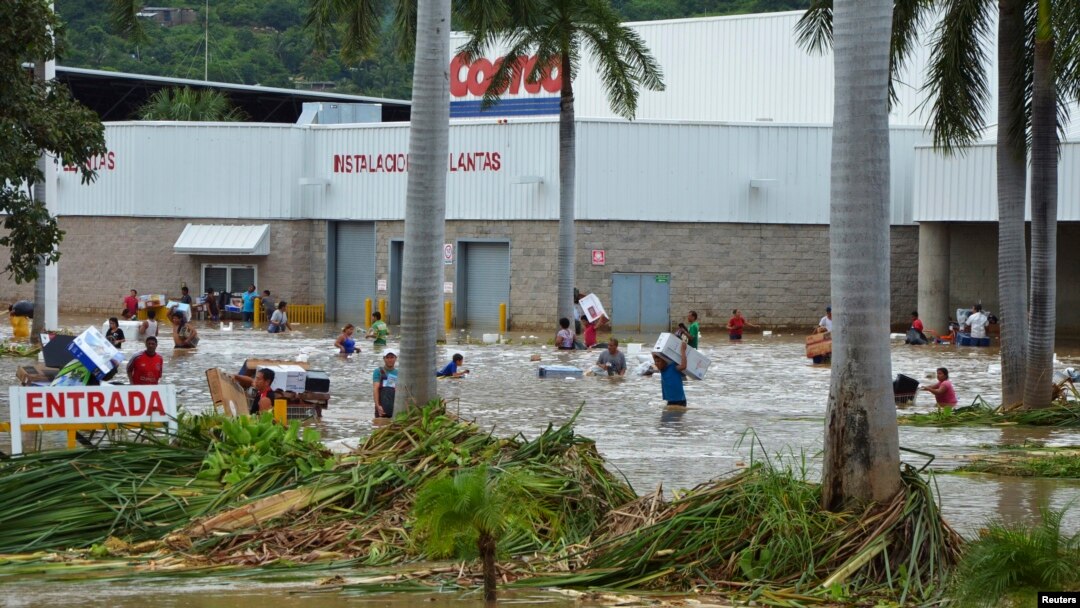 Warga setempat harus melewati jalanan yang terendam banjir setelah berbelanja dari sebuah pusat pertokoan di Acapulco, Meksiko (17/9). Sedikitnya 47 orang dilaporkan tewas dan 40 ribu orang wisatawan terlantar pasca hantaman badai tropis Manuel di kawasan tersebut.