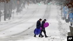 Pedestrians cross a snowy Franklin Street in Chapel Hill, N.C., Jan. 7, 2017, as a winter storm blankets the area with sleet and snow. Some parts of North Carolina received snow, others got rain and sleet.