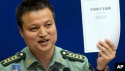 中国国防部发言人杨宇军手持《中国的军事战略》白皮书在新闻发布会上（2015年5月26日）