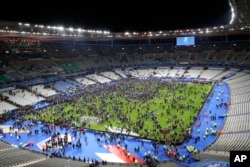 Spectators rush onto the field at Stade de France stadium after an explosion nearby, Nov. 13, 2015.