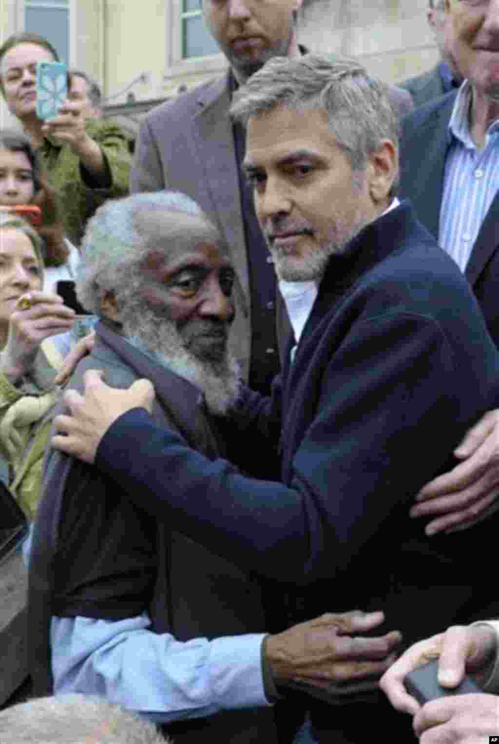 Actor George Clooney embraces activist Dick Gregory during a protest at the Sudan Embassy in Washington, Friday, March 16, 2012. The demonstrators are protesting the escalating humanitarian emergency in Sudan that threatens the lives of 500,000 people. (A