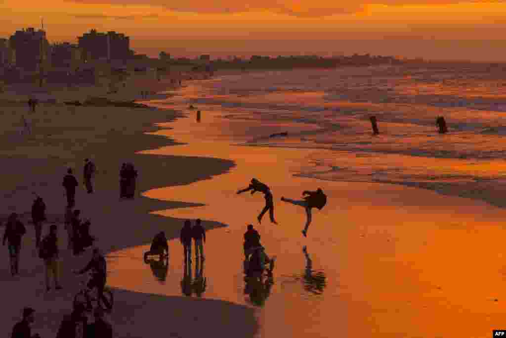 Palestinians make jumps on the beach during the sunset in Gaza City.