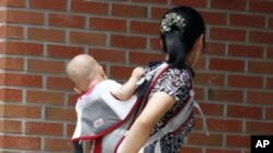 A woman who has escaped from North Korea walks into a building as she carries her child at the Hanawon centre, the state-run official temporary base for defectors from the North, in Anseong. The Hanawon was founded July 8, 1999 to help North Korean defect