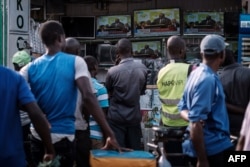 People watch a live broadcast of the announcement of the re-election results by Kenya's Independent Electoral and Boundaries Commission (IEBC) chairman, Wafula Chebukat, on TV at a local electrical shop in Kisumu, Oct. 30, 2017.