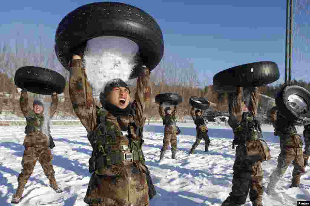 People's Liberation Army (PLA) soldiers pour snow from tires onto their head during a training session in Heihe, Heilongjiang province, China, Dec. 24, 2014.