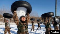 People's Liberation Army (PLA) soldiers pour snow from a tire onto their head during a training session in Heihe, Heilongjiang province, December 24, 2014.