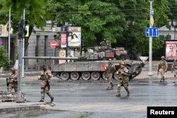 Pejuang kelompok tentara bayaran swasta Wagner menyeberang jalan saat mereka dikerahkan di dekat markas besar Distrik Militer Selatan di kota Rostov-on-Don, Rusia, 24 Juni 2023. (Foto: Reuters)