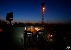 FILE - members of the German border police sit in a van as they check a security camera while monitoring a stretch of the Serbian border with Hungary in the village of Hajdukovo, some 180 kilometers north of Belgrade, Serbia, Feb. 13, 2015.