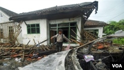 Seorang polisi menginspeksi kerusakan di rumah salah seorang jemaah Ahmadiyah di Cikeusik setelah serangan massal yang menewaskan tiga orang.