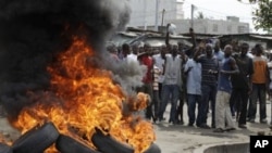Supporters of opposition candidate Alassane Ouattara shout 'We don't want Gbagbo,' as they stand beside a street fire set in protest at incumbent President Laurent Gbagbo remaining in office, in the Koumassi neighborhood of Abidjan, Ivory Coast, 06 Dec 20