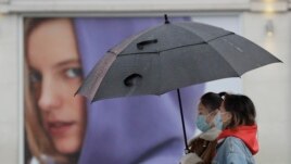 People wear masks to protect against coronavirus as they pass a shop in London, Wednesday, Feb. 3, 2021. (AP Photo/Kirsty Wigglesworth)