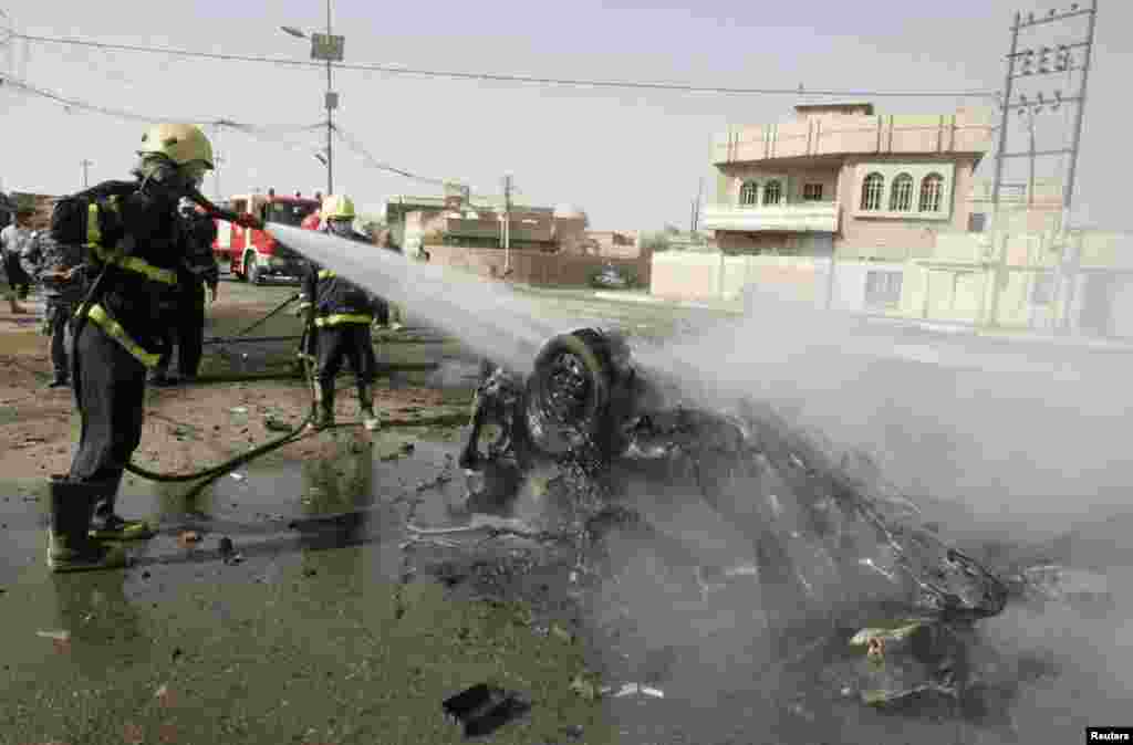 A firefighter hoses down a destroyed vehicle at the site of a bomb attack in Kirkuk, north of Baghdad, Iraq, July 23, 2012. 