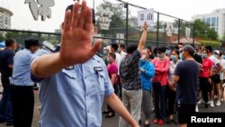 北京市民在一體育中心排隊進行新冠病毒核酸檢測，一名警察做出禁止的手式。（2020年6月17日）