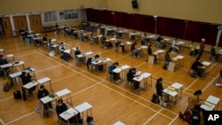 Students wearing masks to help stop the spread of the new coronavirus, sit for the Diploma of Secondary Education (DSE) exams at a school in Hong Kong, Friday, April 24, 2020. Temperature checks and social distancing measures to avoid the spread of…