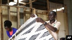 FILE - Manager of Texfad, John Baptist Okello checks a handmade carpet woven from banana fiber threads, at Texfad factory in Sonde, Mukono District, Uganda, Wednesday, Sept. 20 2023. 