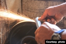 FILE - Sparks come off a grinding wheel while a knife sharpens (Adobe Photo by SELMA)