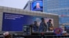 On a Moscow street, an image of Russian President Vladimir Putin is displayed on the facade of a building behind an electronic board promoting contract military service in the Russian army, Dec. 19, 2024. 