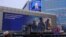 On a Moscow street, an image of Russian President Vladimir Putin is displayed on the facade of a building behind an electronic board promoting contract military service in the Russian army, Dec. 19, 2024.