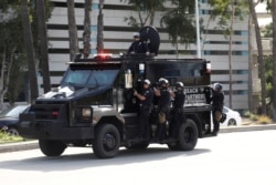 FILE - Police in riot gear are seen on an armored vehicle during nationwide unrest following the death in Minneapolis police custody of George Floyd, in Long Beach, Calif., May 31, 2020.