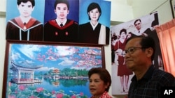 Middle class red shirt supporters Uraiwan Suwannasang, left, and Teerapan Suwannasang, in front of photos of their children at home in Ban Pheu, 17 May 2010