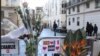 FILE - Flowers are attached to security fences outside Charlie Hebdo headquarters in Paris, one week after the attack on the magazine, Jan. 14, 2015.