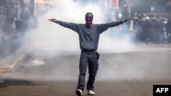 Un manifestant réagissant aux tirs de gaz lacrymogène de la police lors d'une manifestation contre les nouvelles taxes devant le parlement le 20 juin 2024 