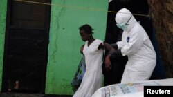 Seorang petugas kesehatan dengan pakaian pelindung membawa seorang pasien Ebola perempuan ke mobil ambulans di Monrovia, Liberia (15/9).