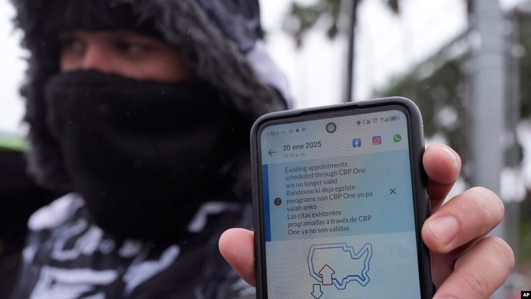 ARCHIVO - Un migrante que busca asilo sostiene la aplicación CBP One que muestra que su cita fue cancelada después de que el presidente Donald Trump asumió el cargo, el lunes 20 de enero de 2025, en Matamoros, México.