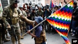 Un simpatizante del ex presidente Evo Morales se arrodilla frente a los soldados que custodian una calle en el centro de La Paz, Bolivia, el viernes 15 de noviembre de 2019. 