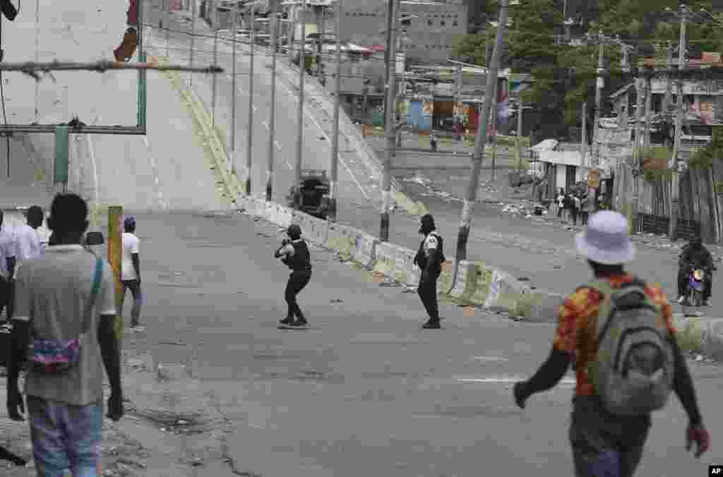 La gente observa cómo agentes de policía intercambian disparos con pandillas en Puerto Príncipe, Haití.