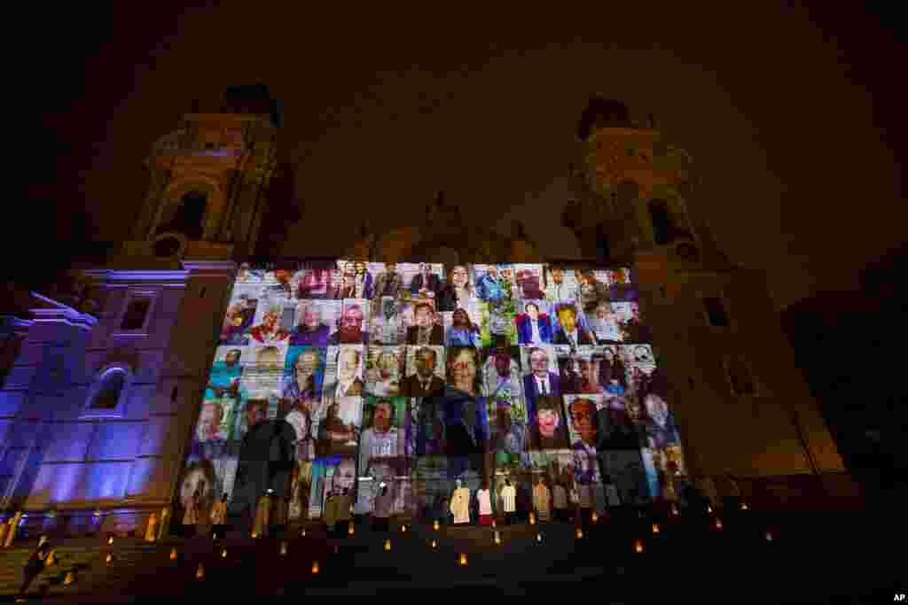 El arzobispo de Lima, Carlos Castillo (centro) balancea un incensario cerca de los retratos de las v&#237;ctimas del COVID-19 proyectados en la fachada de la Catedral de Lima durante una misa dedicada a ellos. Noviembre 1, 2020.