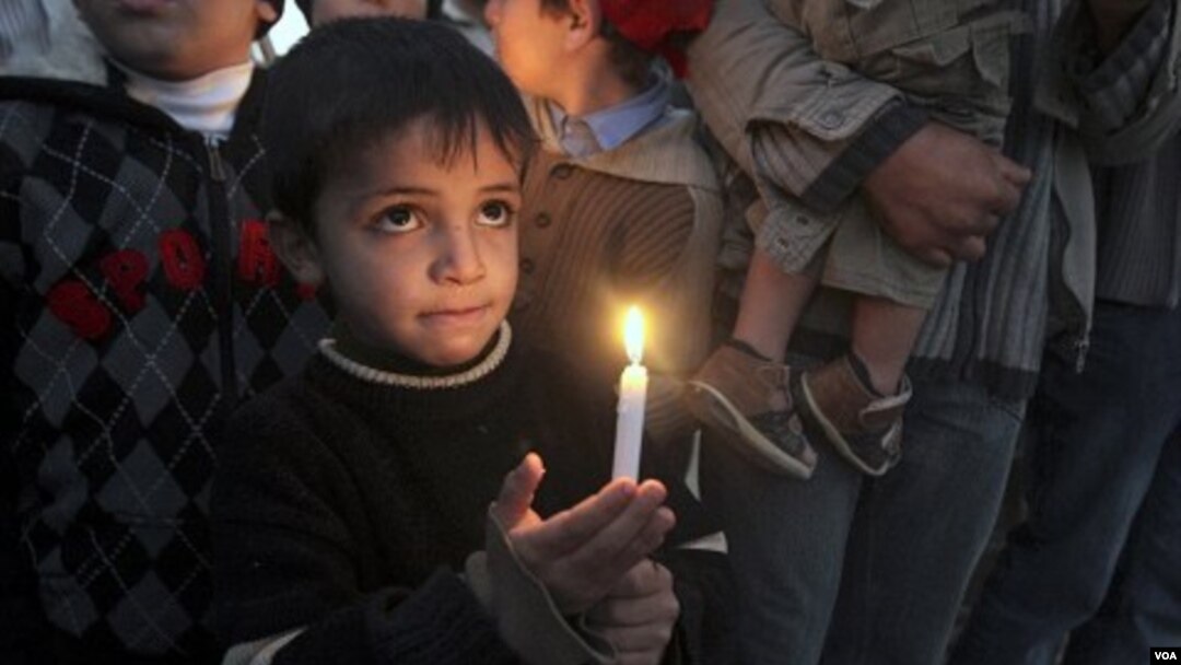 Seorang anak laki-laki Palestina memegang lilin dalam peringatan 2 tahun serangan tiga minggu Israel ke Gaza, 27 Desember 2010.