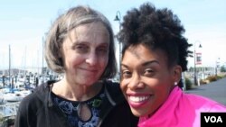 Angela Tucker and her adoptive mom, Teresa Burt, pause during a walk on the Bellingham waterfront. (Claire Morin-Gibourg/VOA)