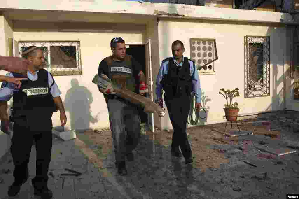 An Israeli police explosives expert carries the remains of a rocket after it was fired from the Gaza Strip and landed in the southern town of Ofakim November 18, 2012