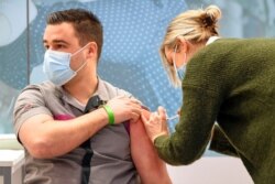 A health care worker, left, is administered a shot of the Pfizer-BioNTech coronavirus vaccine at a mass vaccination center in Veghel, Netherlands, Jan. 6, 2021.