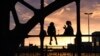 Siluet dua perempuan terlihat saat menikmati suasana menjelang matahari terbenam dekat jembatan di kota Munich, Jerman.