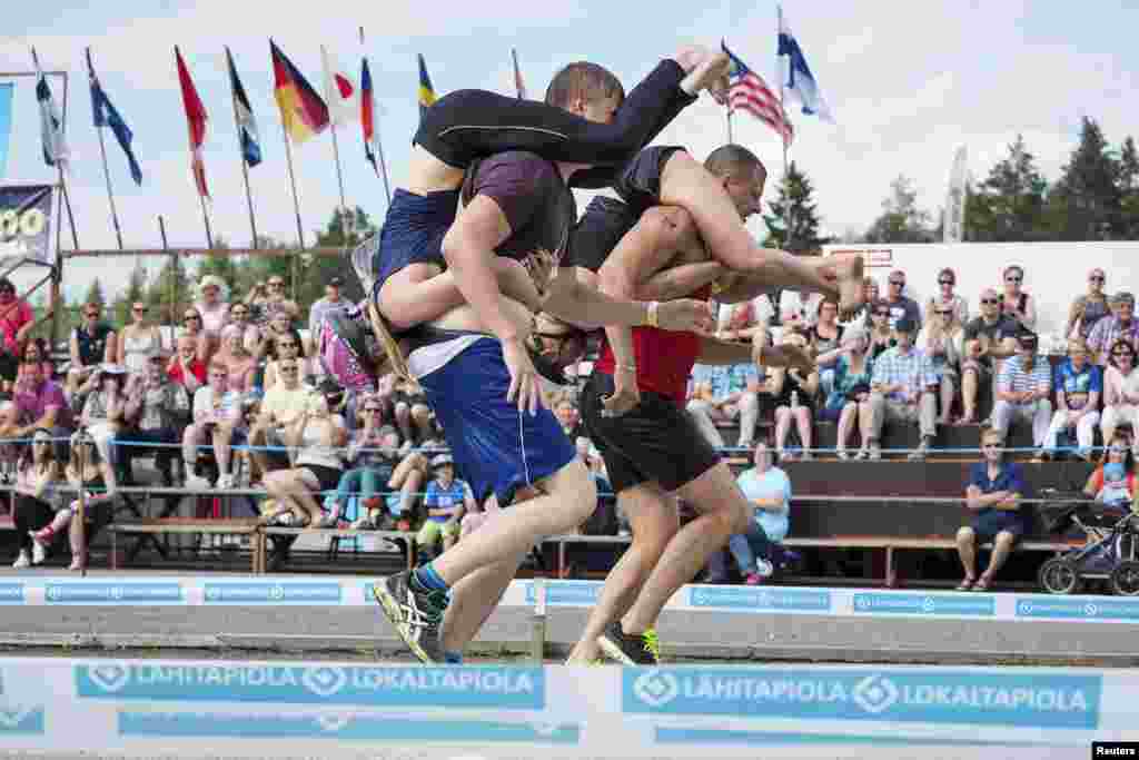 Tia Rope and Joonas Saukkonen (L) and Katja Hyvarinen and Jukka Podduikin, all of Finland, compete during the Wife Carrying World Championships in Sonkajarvi, Finland, July 2, 2016.