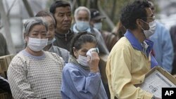 An elder woman wipes her eyes in long lines for food at an evacuation shelter in Koriyama, Fukushima prefecture, Japan, April 2, 2011