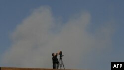 Триполи: телеоператор снимает клубы дыма, которые подымаются из разбомбленного авиацией НАТО здания командного центра