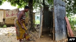 Une femme nettoie ses toilettes dans le quartier de Kindele à Kinshasa le 17 novembre 2017.