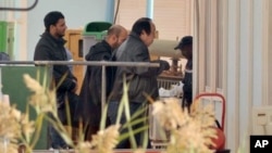 An unidentified person is followed by Algerian officials as they enter a morgue holding the bodies of the persons killed during the hostage situation at the gas plant, in Ain Amenas, Algeria, January 21, 2013. (AP)